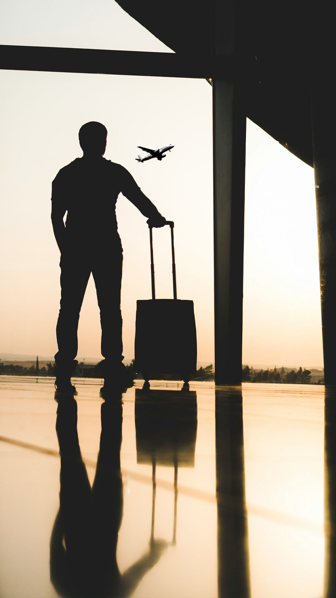 A man standing inside the airport holding his luggage